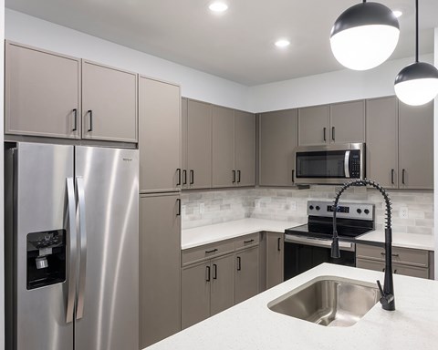 A modern kitchen with a stainless steel refrigerator and a sink.